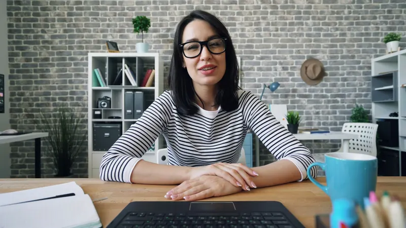A woman talking on a video call at her desk in an office