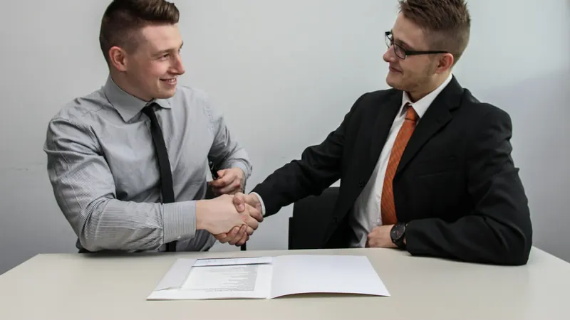 Two businessmen shaking hands and smiling in an office