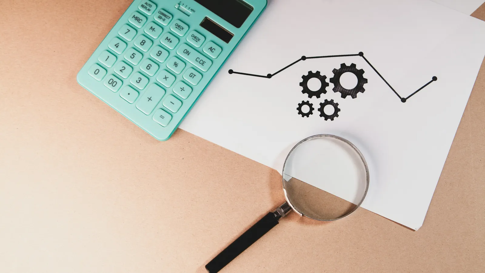 A calculator, magnifying glass and charts on a desk